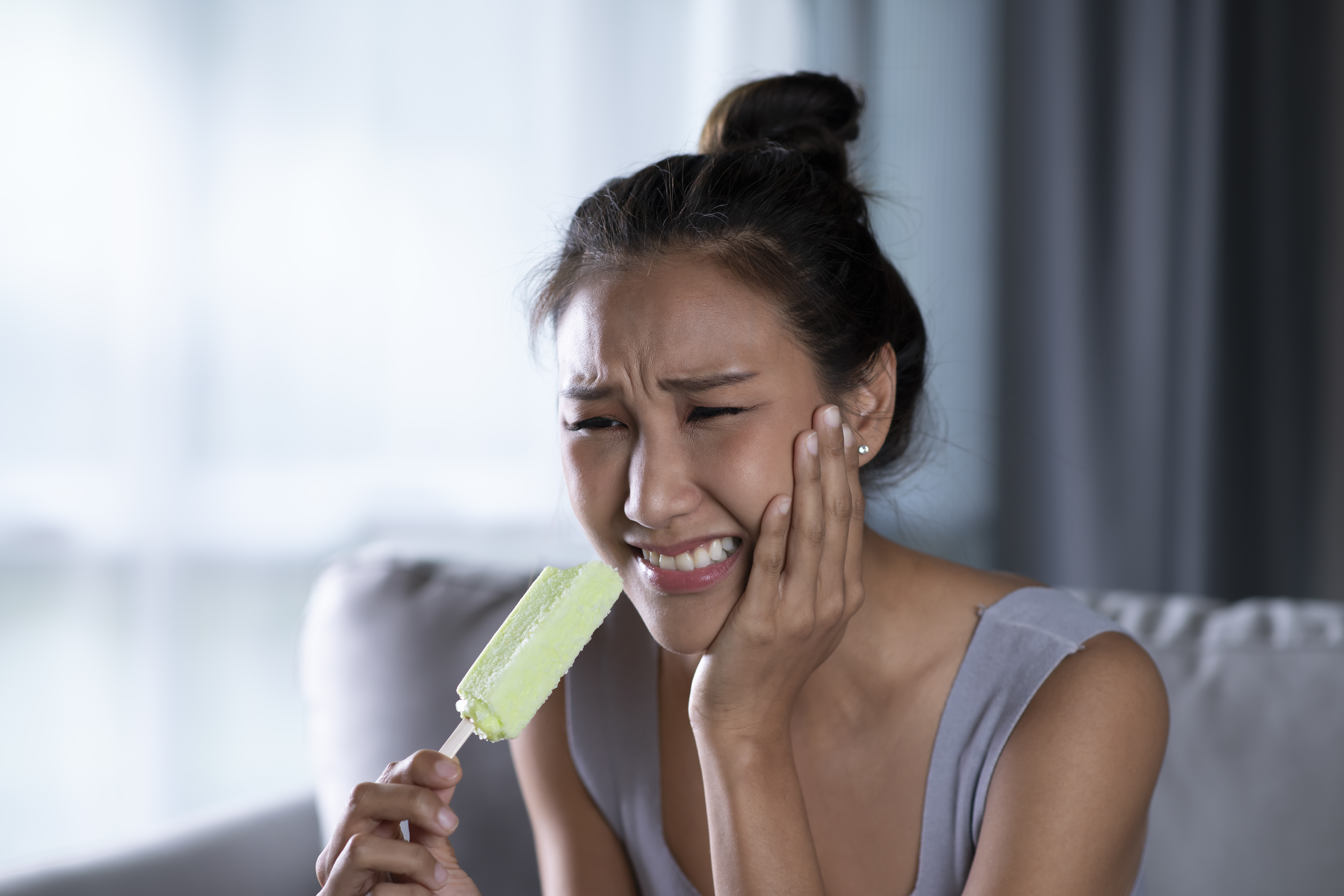 A woman experiencing sudden tooth sensitivity
