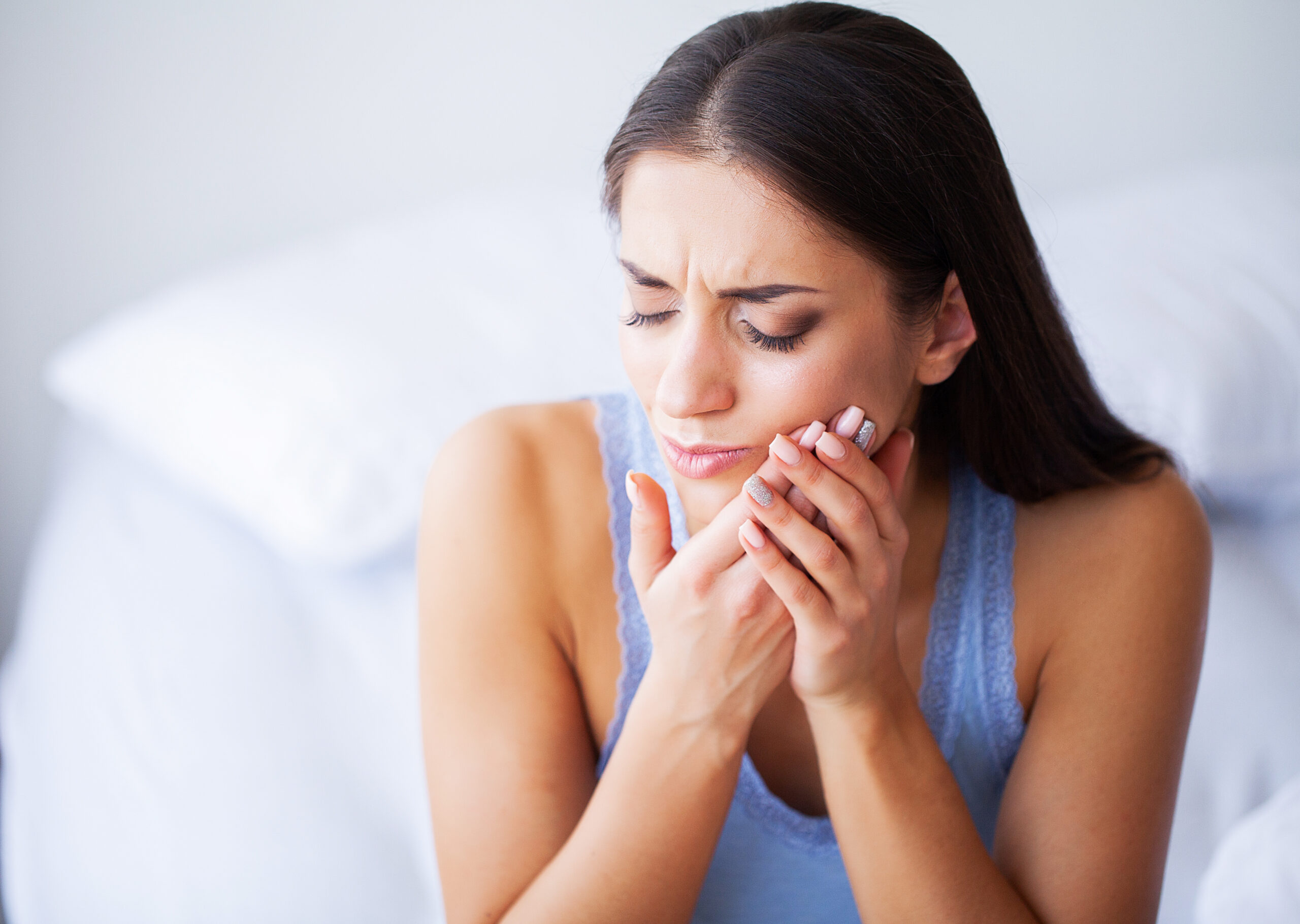 A woman experiencing severe tooth pain with no insurance