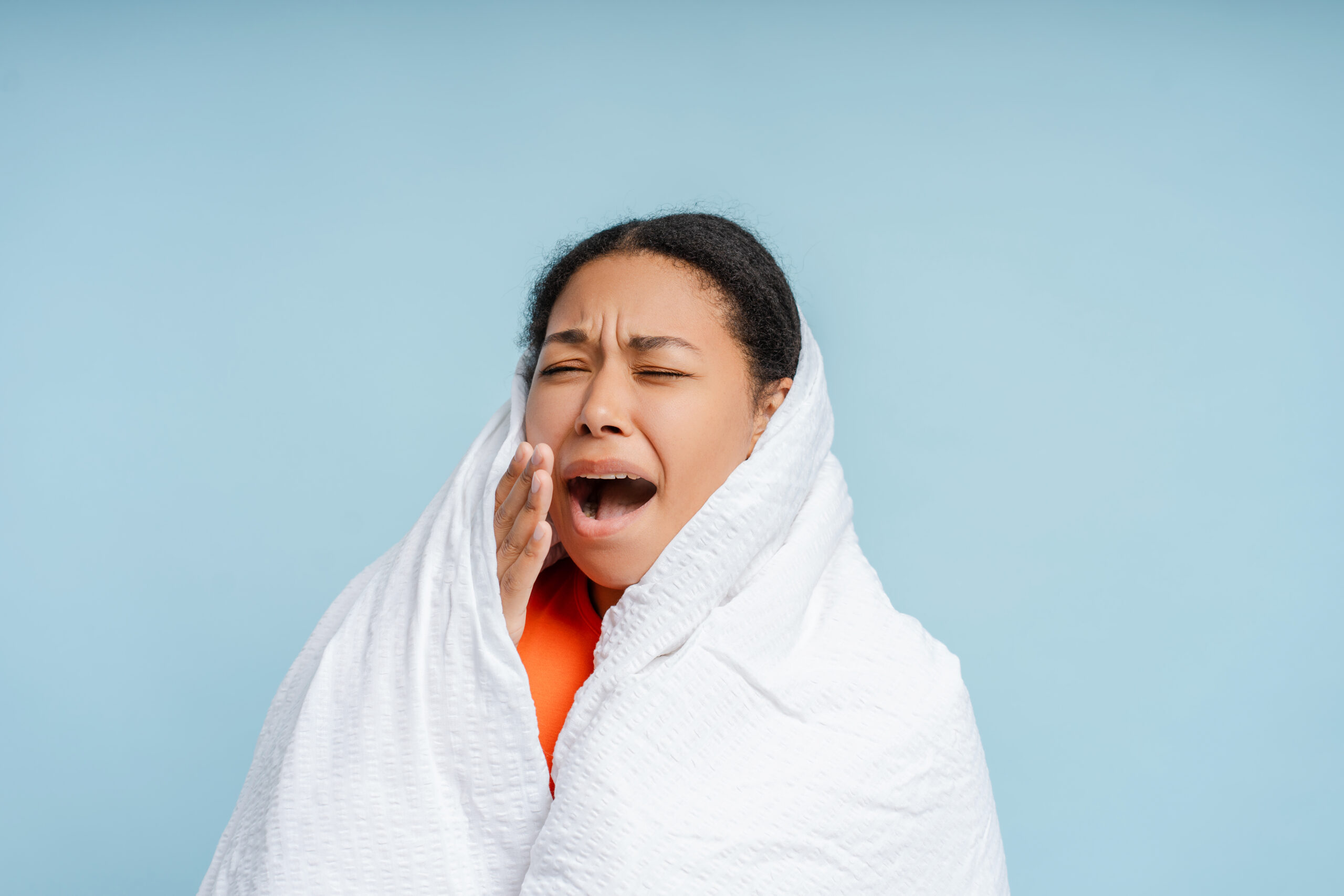 A woman wondering, "why do my teeth hurt when I'm sick?"