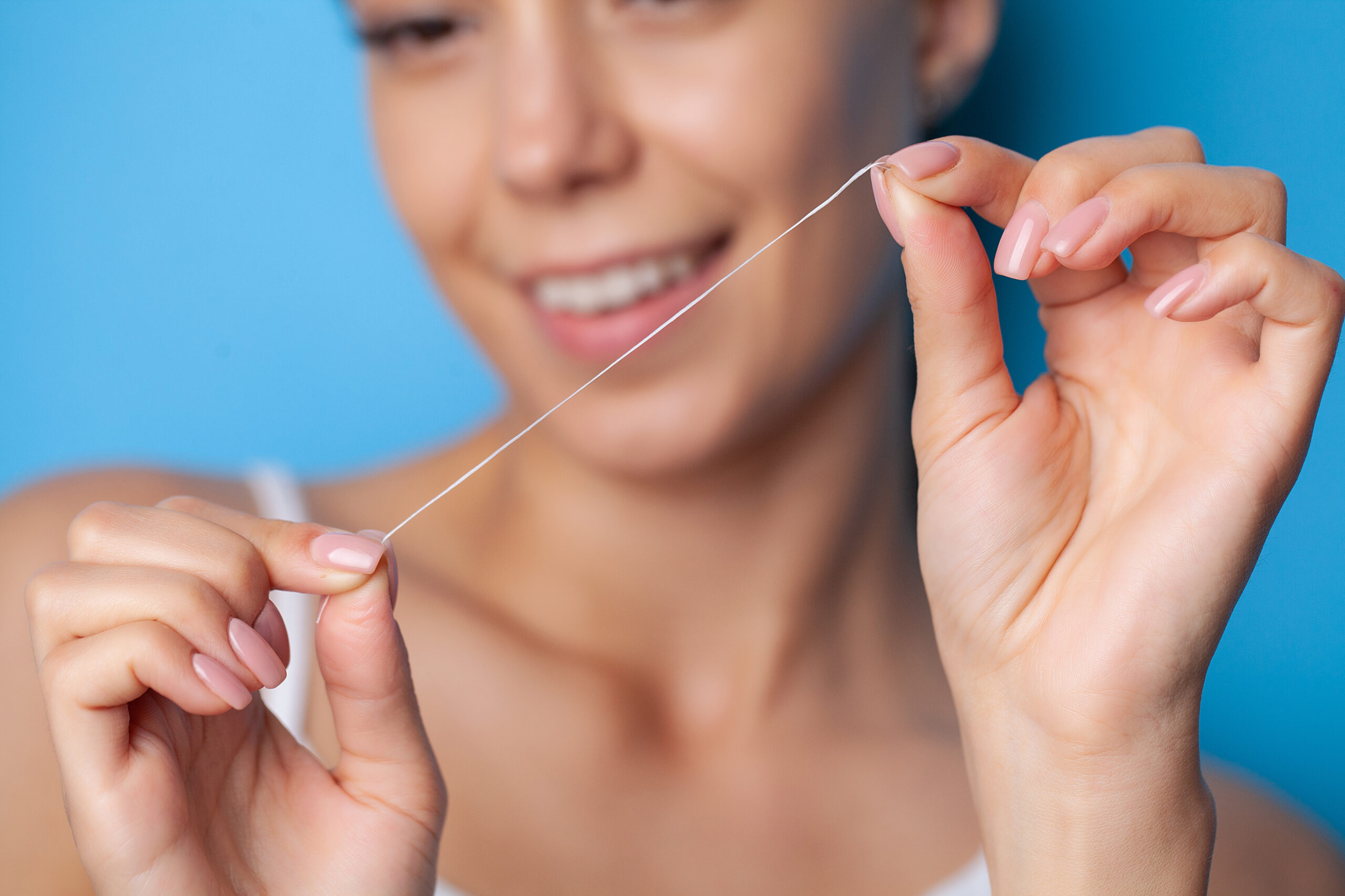 A woman holding floss and wondering, "how often should you floss?"