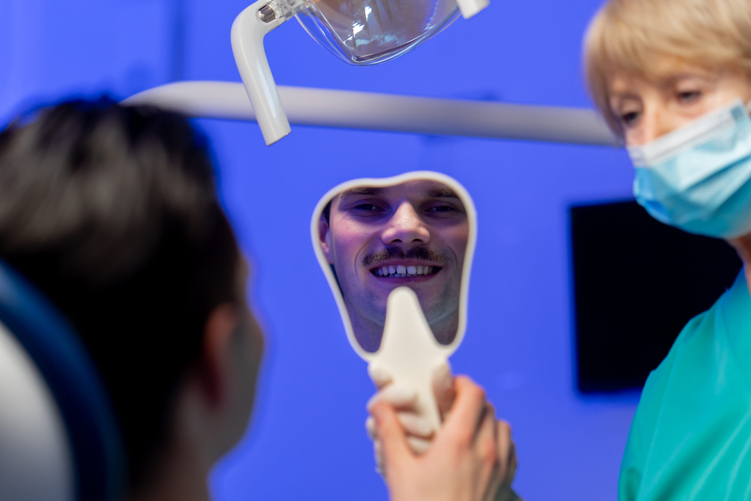 A man looking in the mirror and asking himself, "is b1 tooth shade too white?"