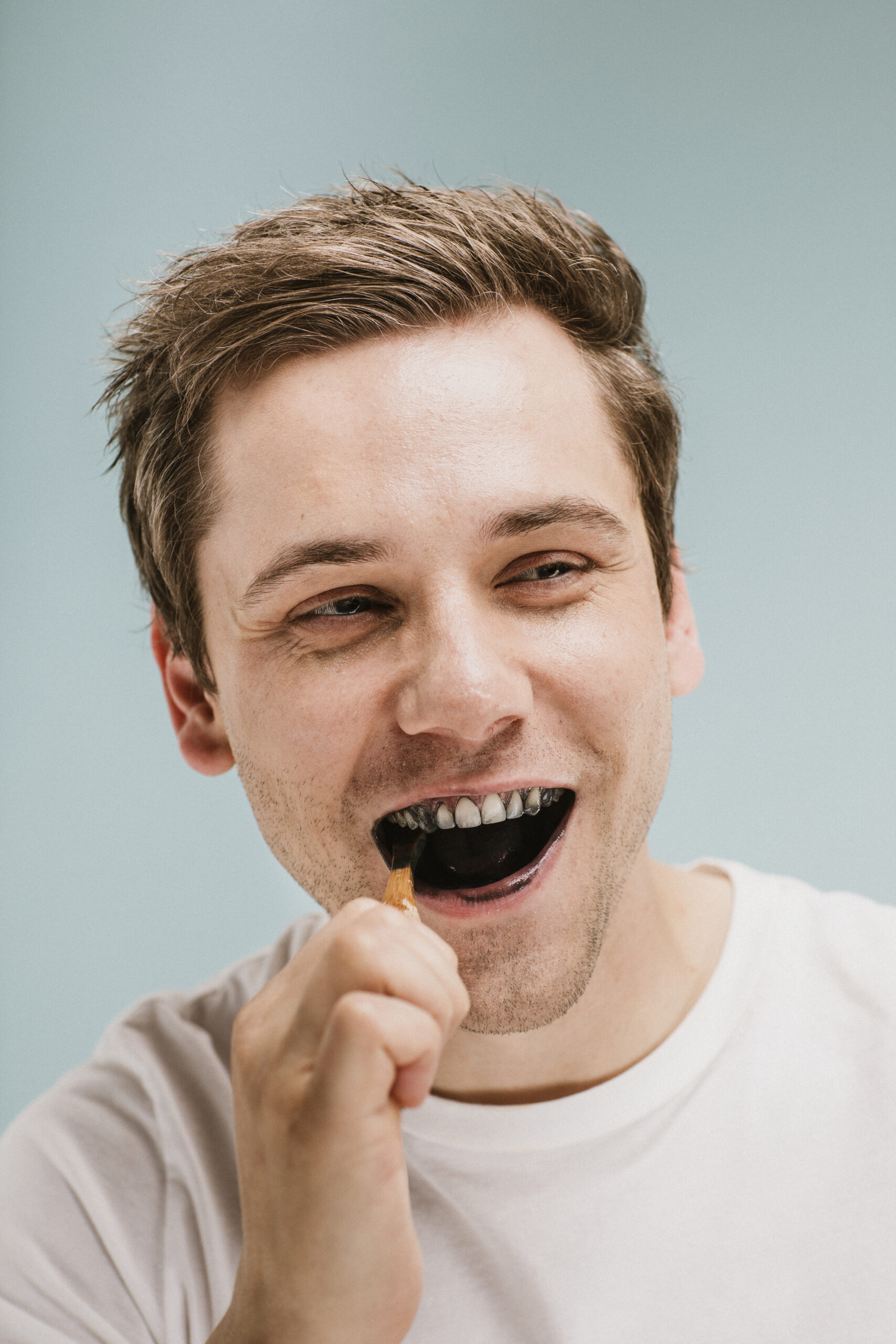 A man brushing his teeth after having an intrinsic tooth stain removed.