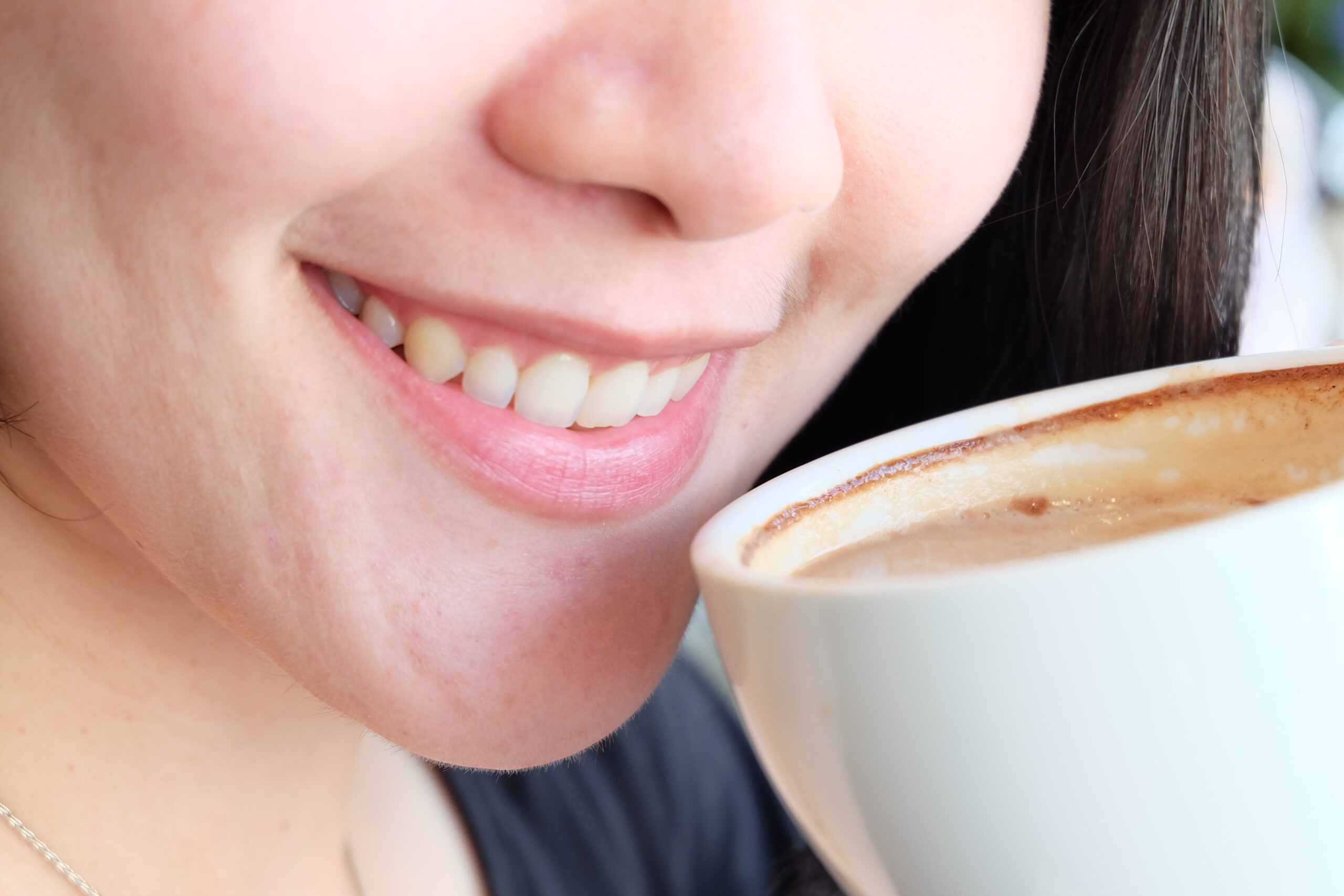 A woman drinking coffee thinking, "is coffee bad for your teeth?"