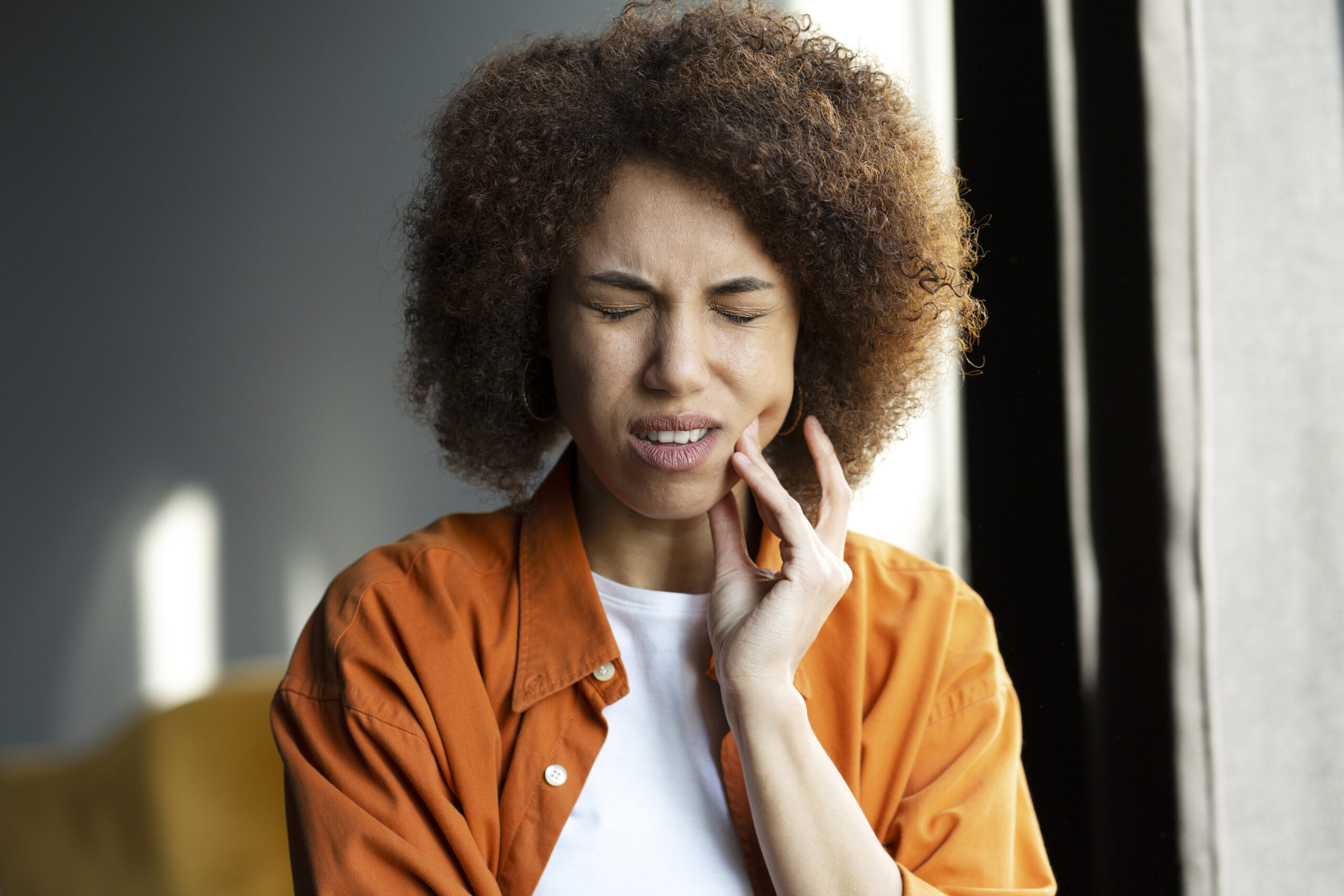 A woman in pain thinking, "my teeth ache."